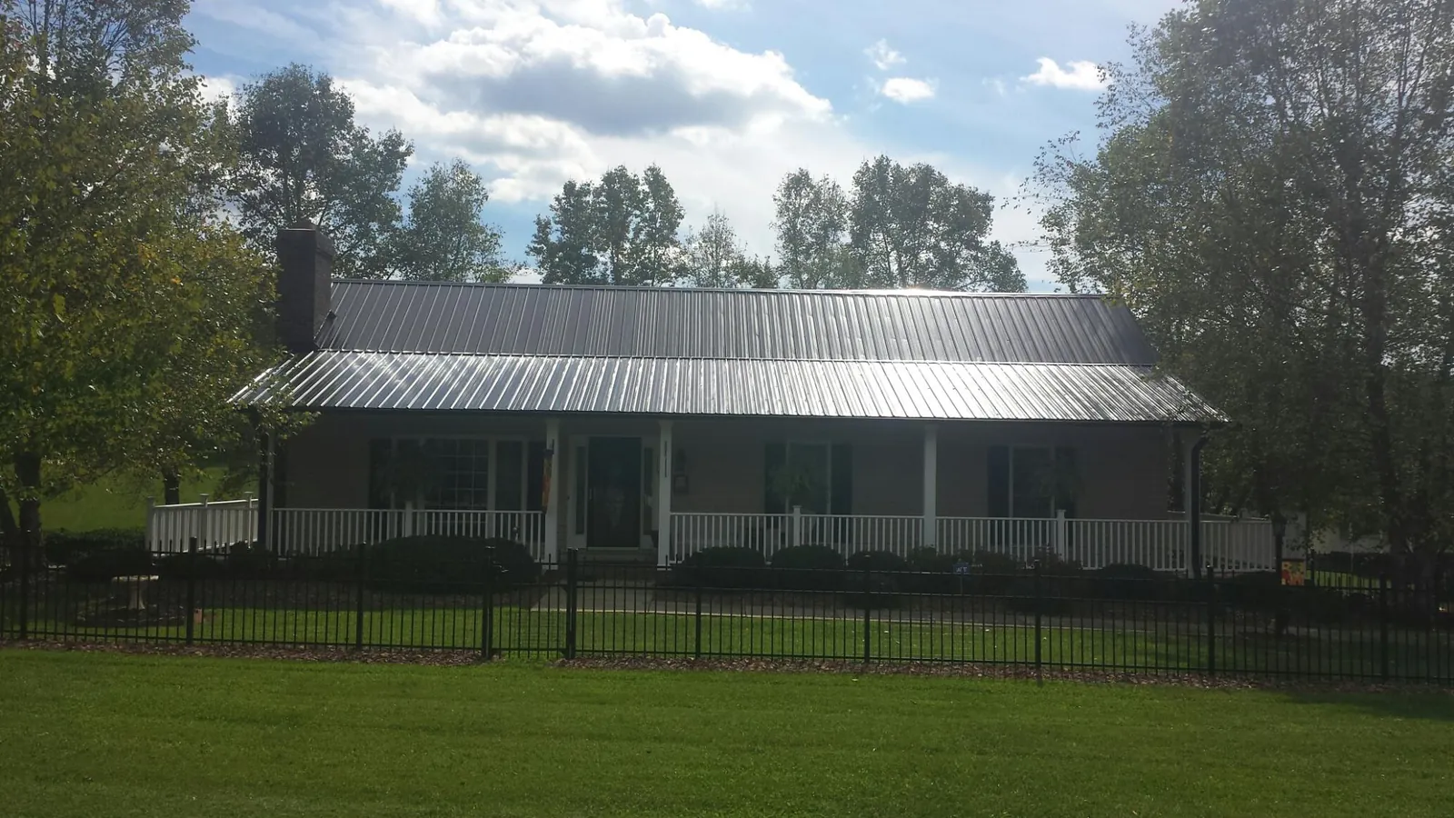 Gray metal roof on a brick ranch with a full width front porch — Gutter Guard Installation work by our crew in Garden Valley