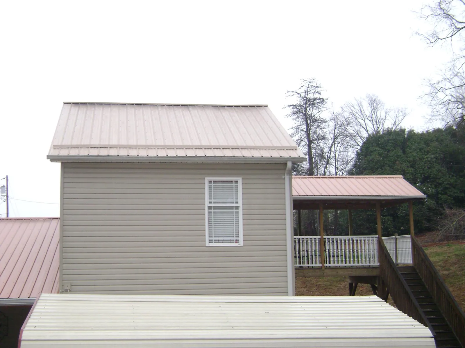 Tan metal roofs on a two story addition and attached porch, from a Roof Replacement job in Garden Valley